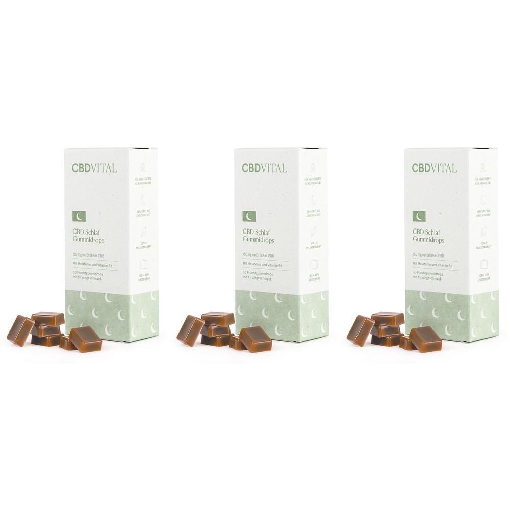 Drei Schachteln CBD VITAL Schlaf CBD Gummidrops mit Melatonin, daneben liegen einige Gummis.