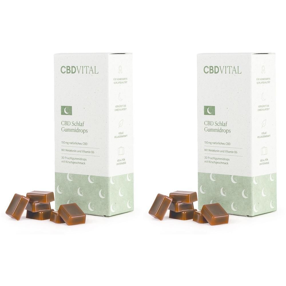 Zwei Schachteln CBDVITAL Schlaf Gummidrops mit Melatonin und Vitamin B6. Einige Gummis liegen daneben.
