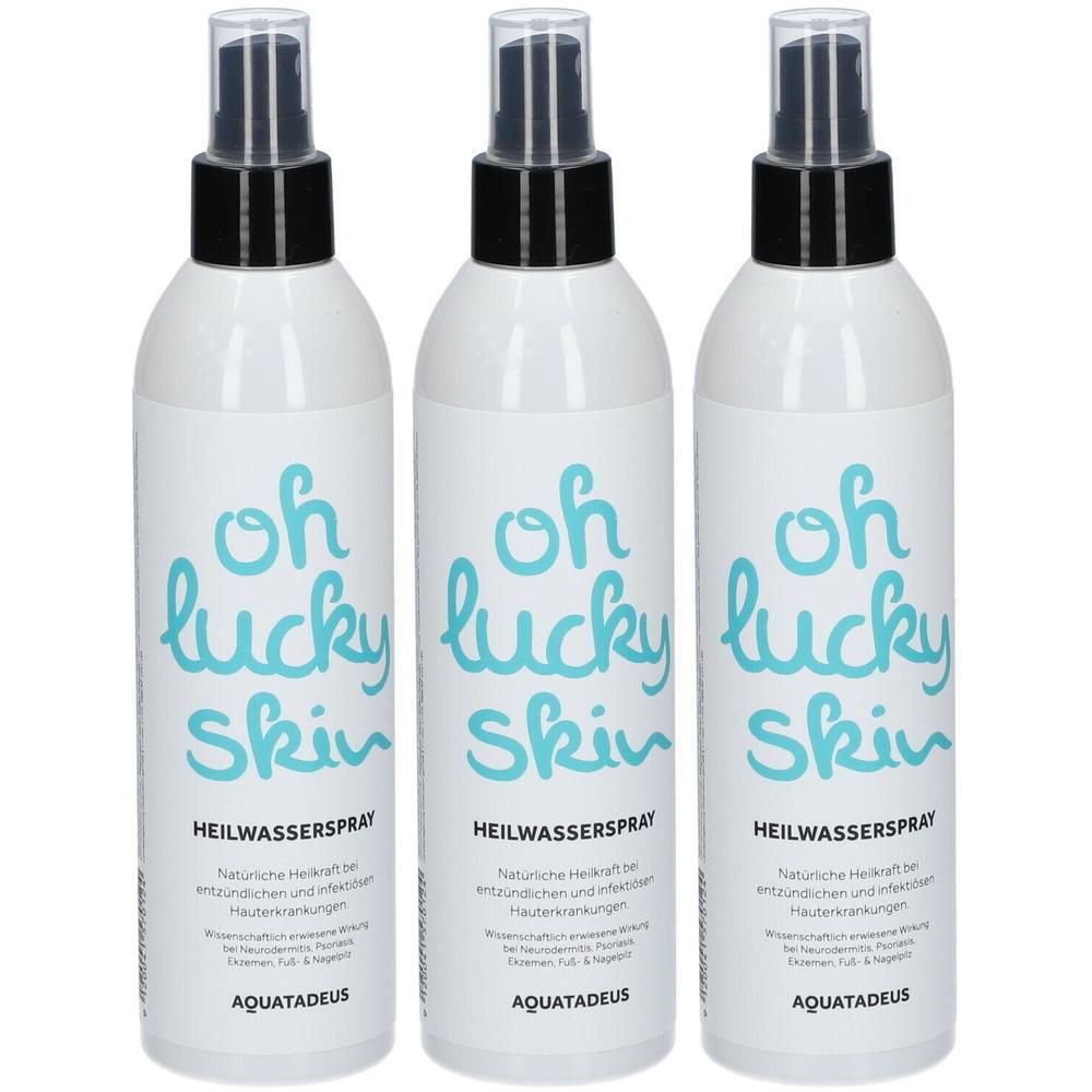 Drei weiße Sprühflaschen mit schwarzem Sprühkopf. Blaue Schrift "oh lucky skin".