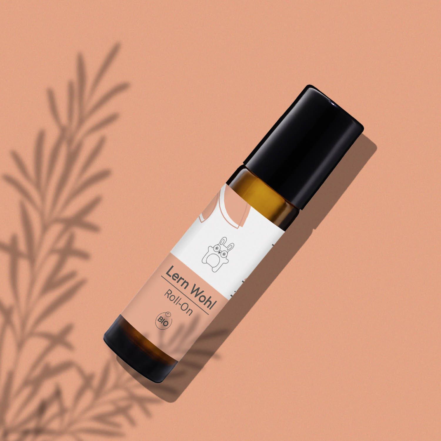 Ein kindgesund® Lern Wohl Roll-On in brauner Glasflasche mit schwarzem Verschluss, schräg liegend.