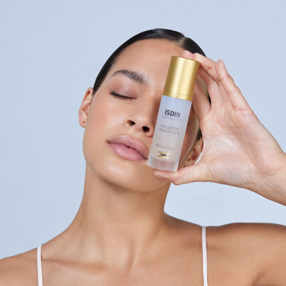 Frau hält eine Flasche Isdin Isdinceutics Hyaluronic Concentrate Serum vor ihr Gesicht.