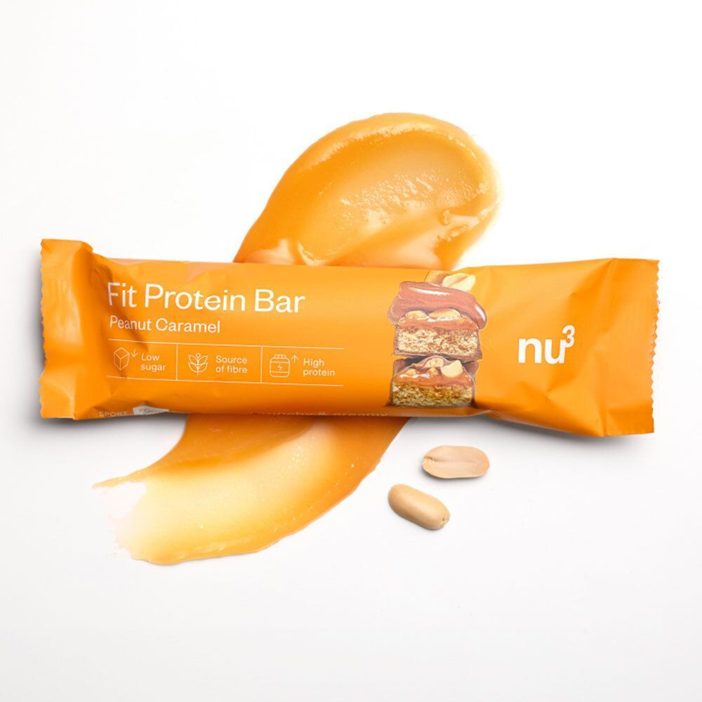 Ein nu3 Fit Protein Riegel, Peanut Caramel, umgeben von Karamellcreme und Erdnüssen.