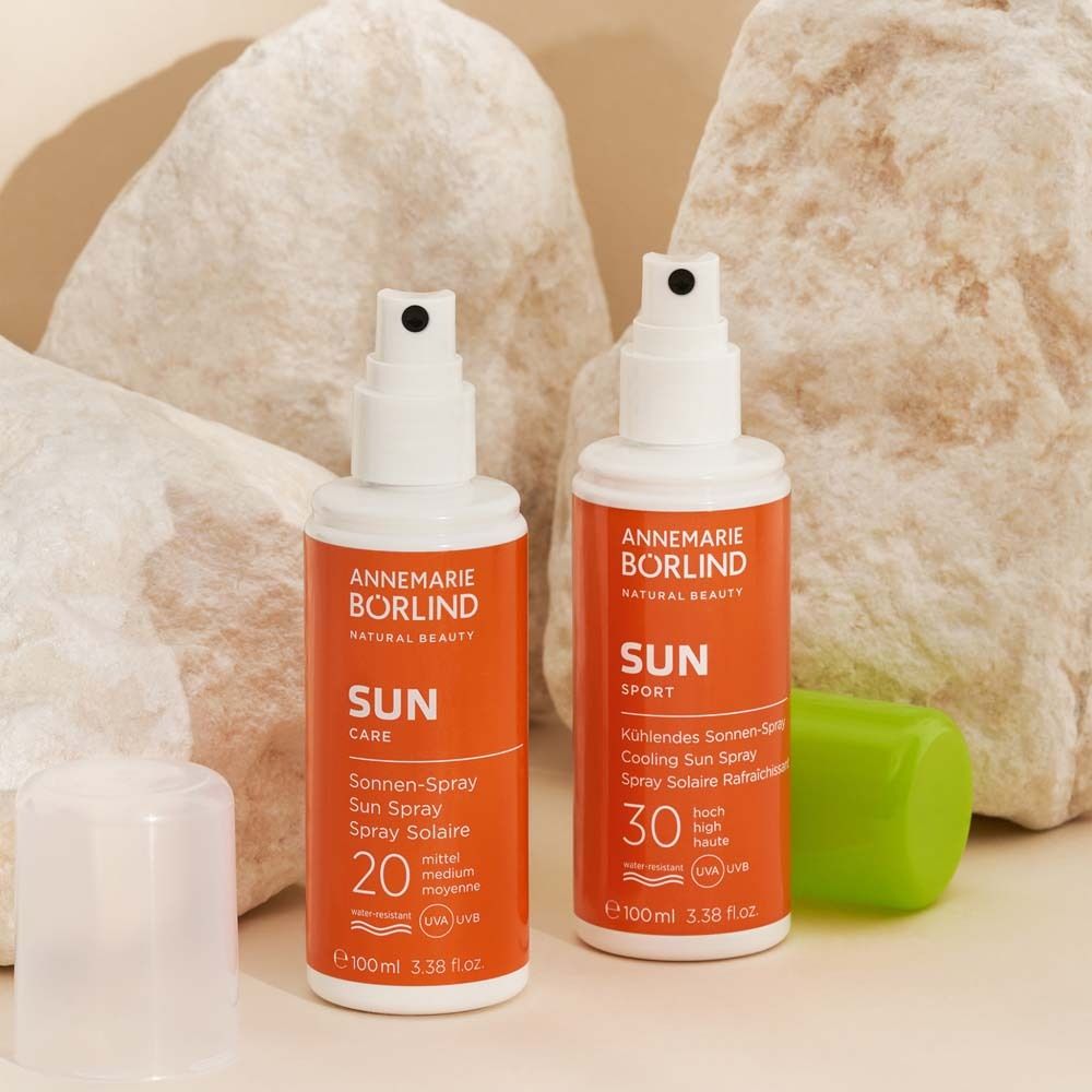 Zwei Flaschen ANNEMARIE BÖRLIND Sun Spray. Orangefarbene Flaschen mit weißem Deckel. Text: SUN CARE, 20, 30.