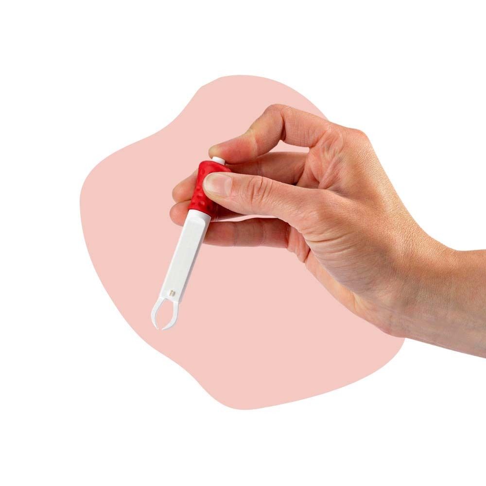 Hand hält Zeckenzange. Zange mit rotem Griff. Rosa Hintergrund.