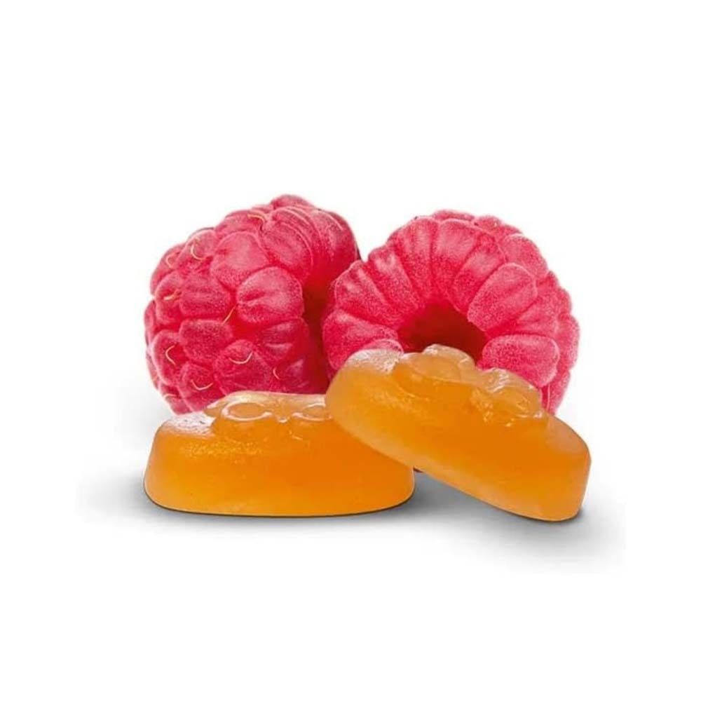 Nahaufnahme von Himbeeren und Pastillen. Zwei Himbeeren und zwei orangefarbene Pastillen.