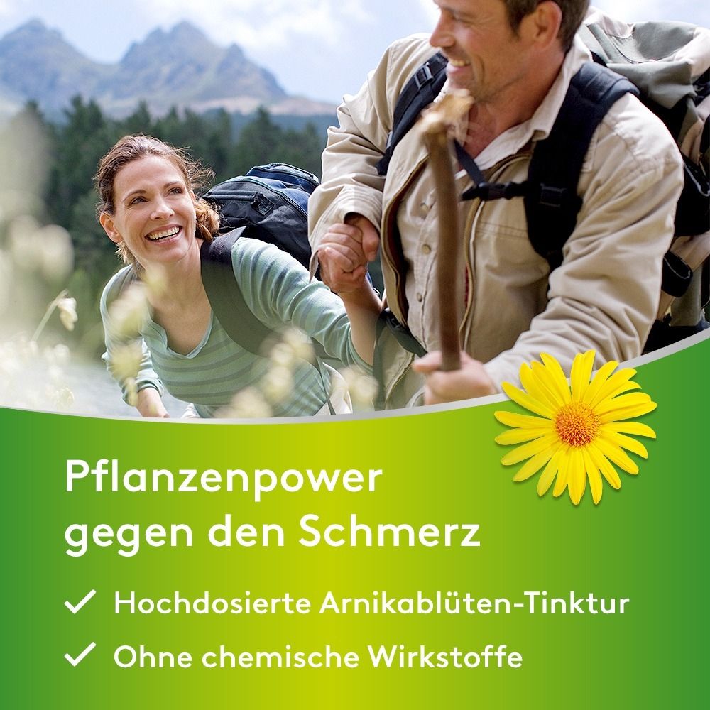 Zwei Wanderer mit Rucksäcken in bergiger Landschaft. Ein Arnika-Blüten-Symbol ist sichtbar.