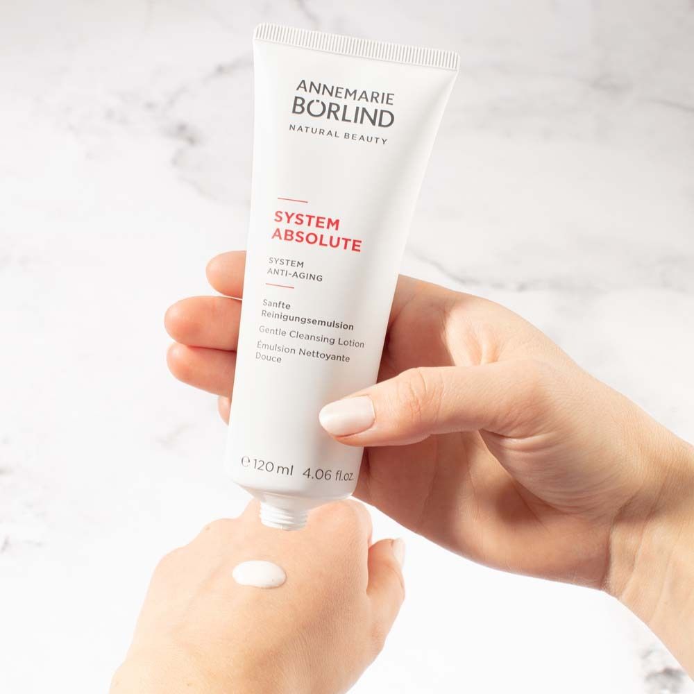 Weiße Tube mit Produkt. Produkt wird auf die Hand aufgetragen. Goldfarbener Verschluss.