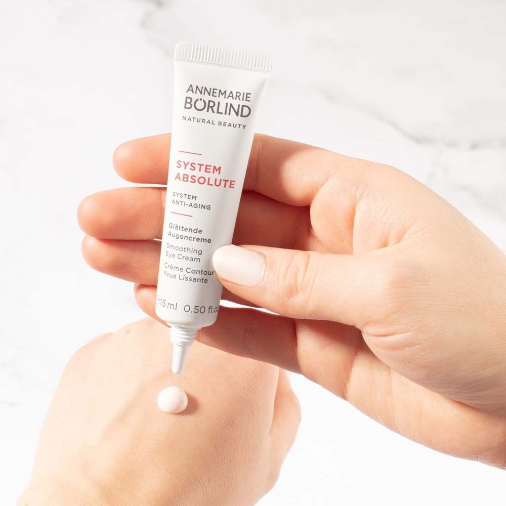 Creme-Tube in Hand. Creme-Tropfen auf Hand. Text: ANNEMARIE BÖRLIND, SYSTEM ABSOLUTE, Glättende Augencreme.