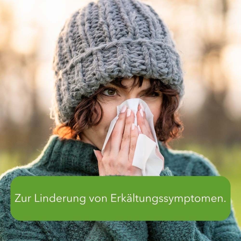 Frau mit Mütze und Taschentuch. Text: Zur Linderung von Erkältungssymptomen.