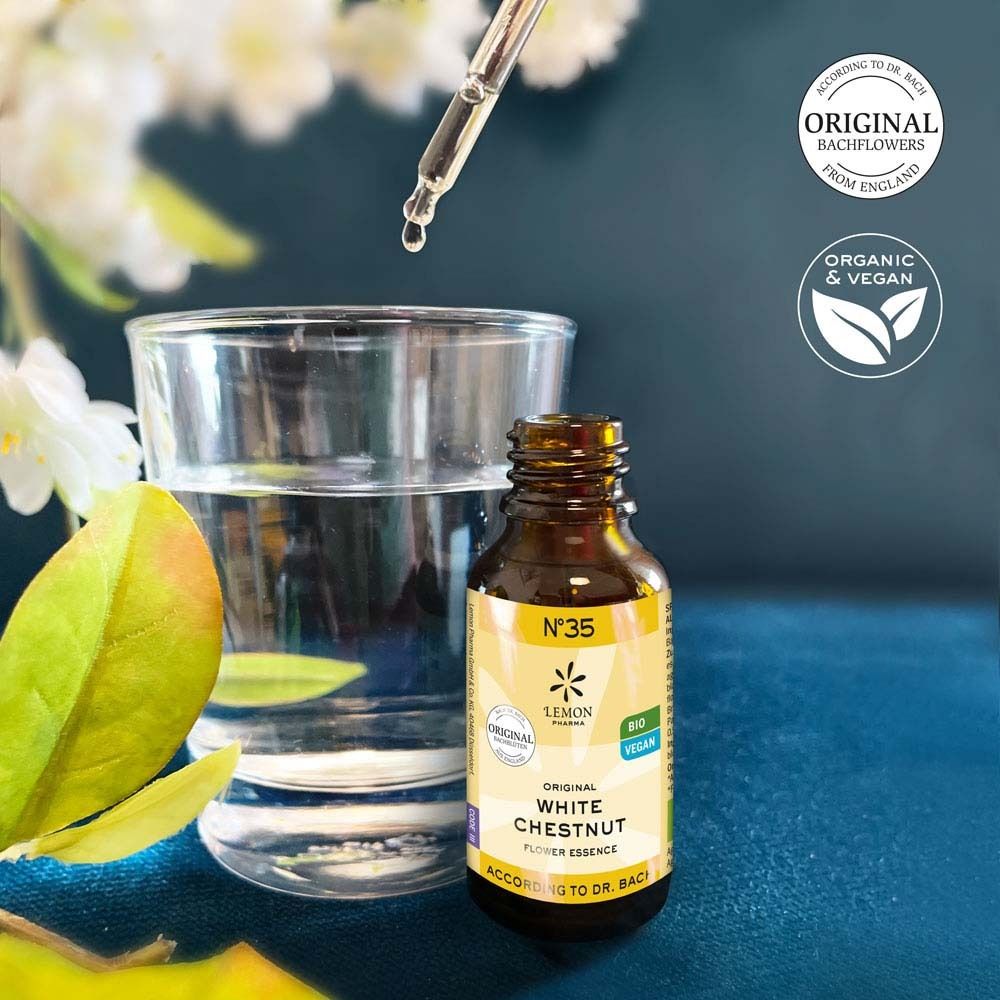 Braune Glasflasche mit gelbem Etikett, Tropfen fallen in ein Glas Wasser. Aufschrift: White Chestnut Flower Essence. Mit Tropfer.