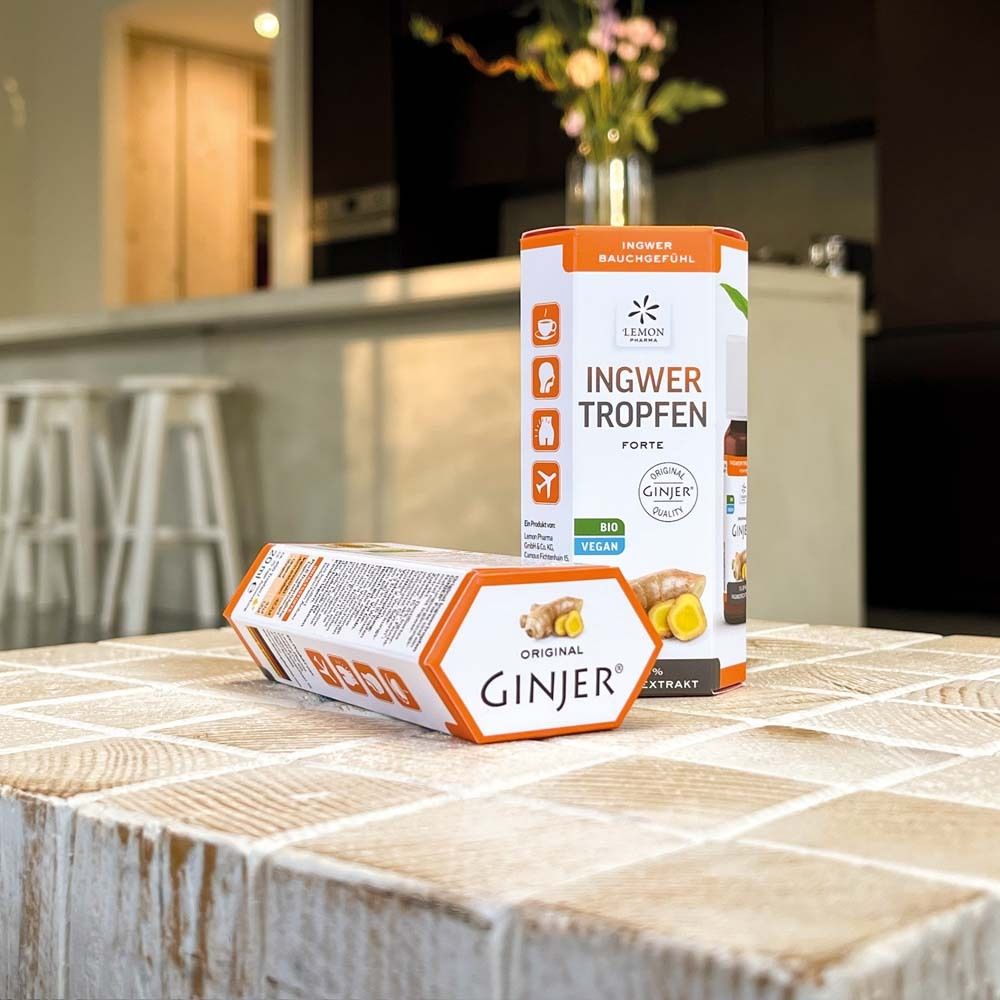 Zwei Produktverpackungen auf einem Tisch. Eine steht, die andere liegt. Aufdruck: „GINJER® FORTE“ und Ingwer-Abbildung.