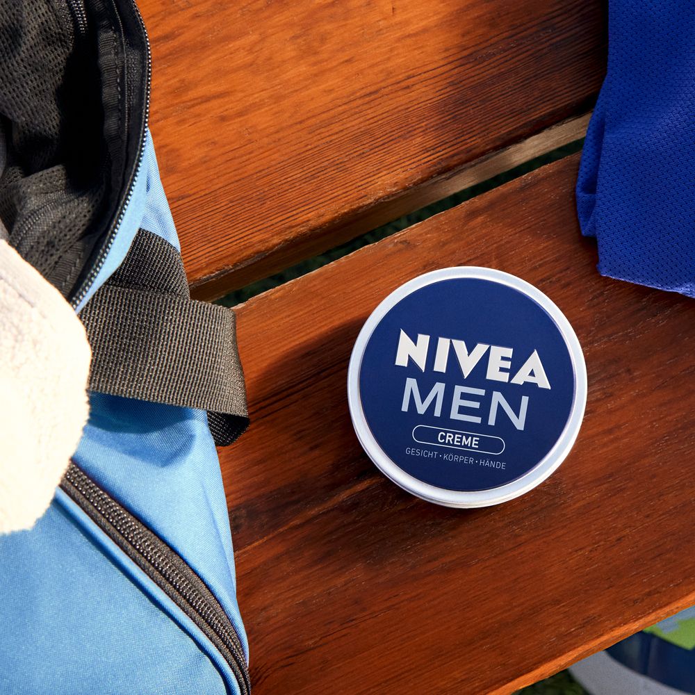 NIVEA MEN Creme Dose auf einer Holzoberfläche neben einer Sporttasche.