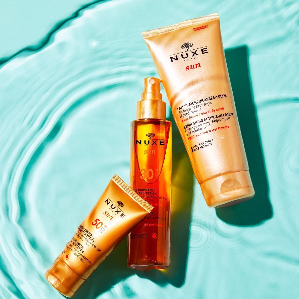 Drei NUXE Sun Produkte: Lotion, Spray und Creme. Gelbe Verpackungen mit roter Schrift. Auf blauem Hintergrund.