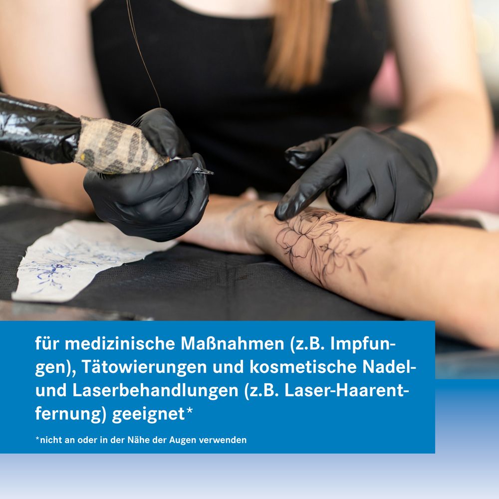 Tätowierer tätowiert. Text: für medizinische Maßnahmen geeignet. Emulus 25 mg/g + 25 mg/g Creme.