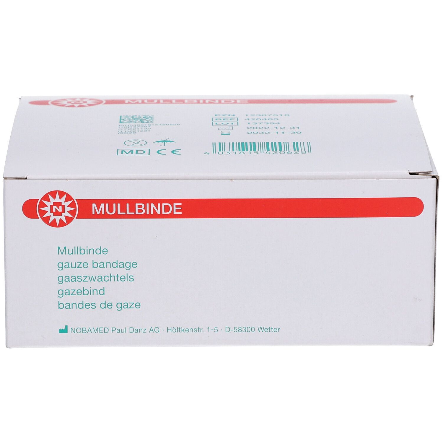 Weiße Verpackung mit rotem Streifen und 'Mullbinde'. Produktbezeichnung in verschiedenen Sprachen. Gaze-Bandage.