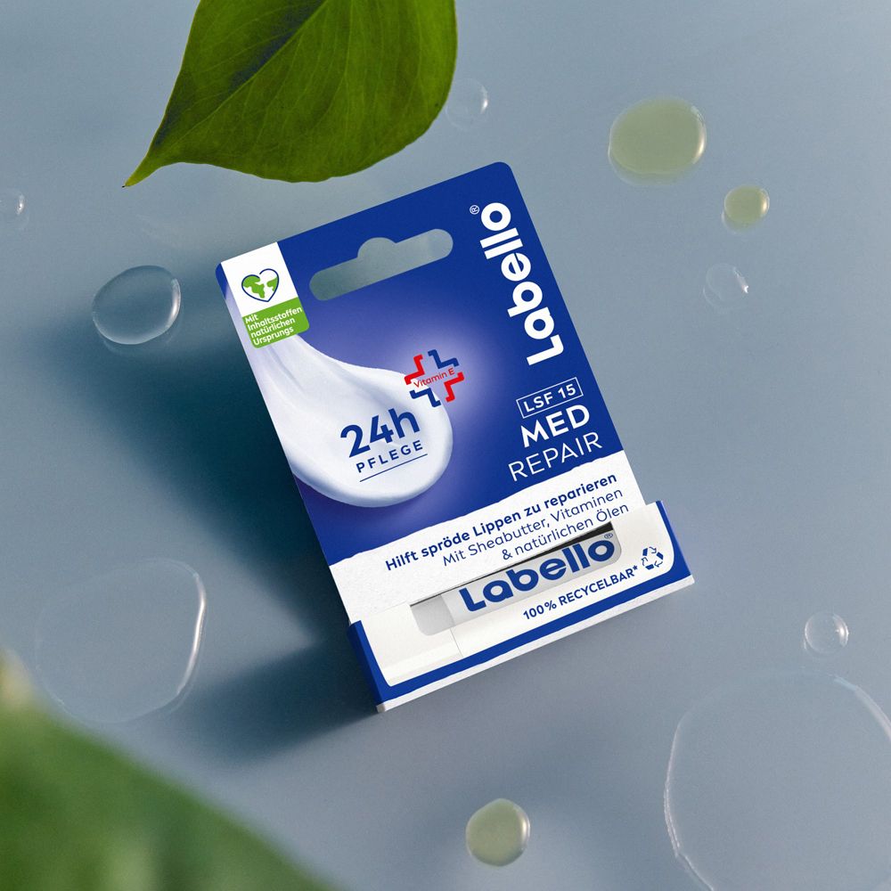 Labello Med Repair Lippenbalsam in Verpackung auf blauem Hintergrund mit Wassertropfen.