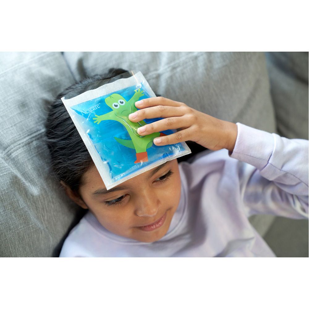 Kind mit einem blauen Nexcare ColdHot Therapy Pack happy kids mit Krokodil-Design auf der Stirn.