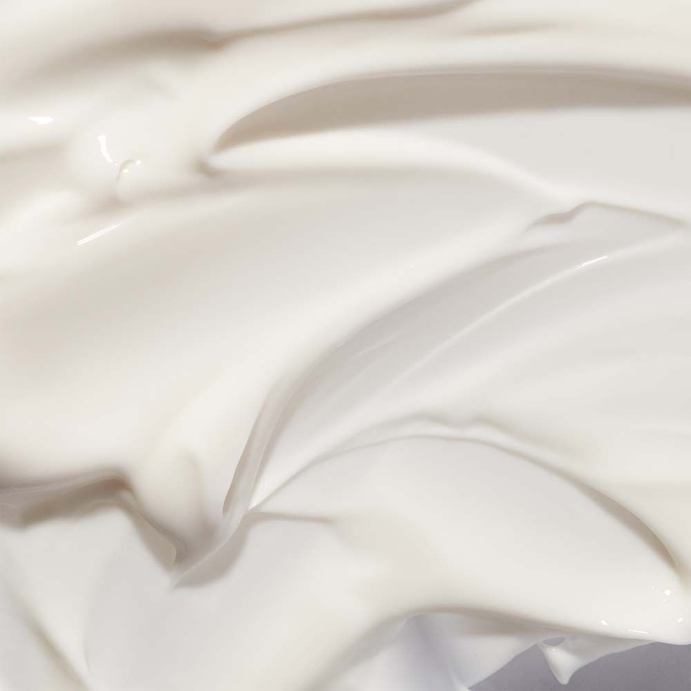 Nahaufnahme von weißer Handcreme. Cremige Textur, wellenförmig. Keine Beschriftung sichtbar.