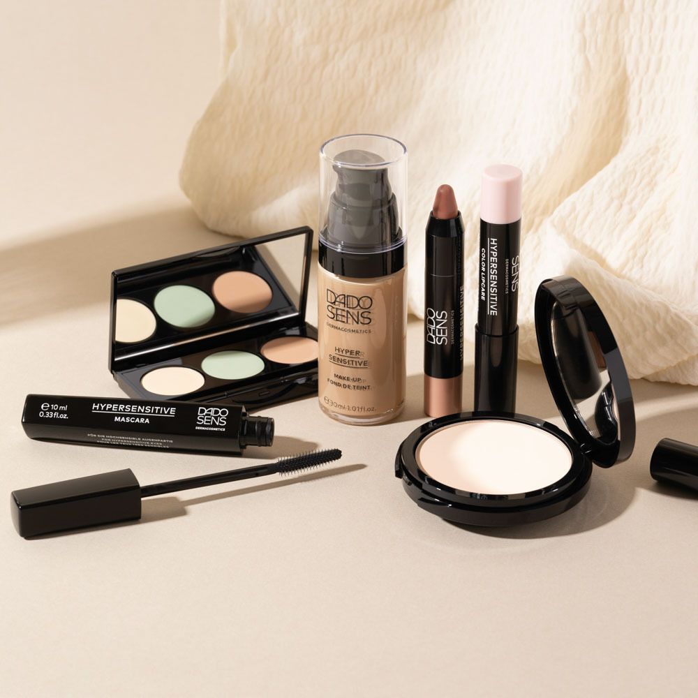 Kosmetikprodukte: Mascara, Puder, Concealer, Foundation, Lippenstift. Auf hellem Untergrund.