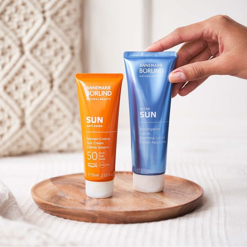 Zwei Tuben Sonnencreme auf Holztablett. Orange und blau. Text: ANNEMARIE BÖRLIND SUN.