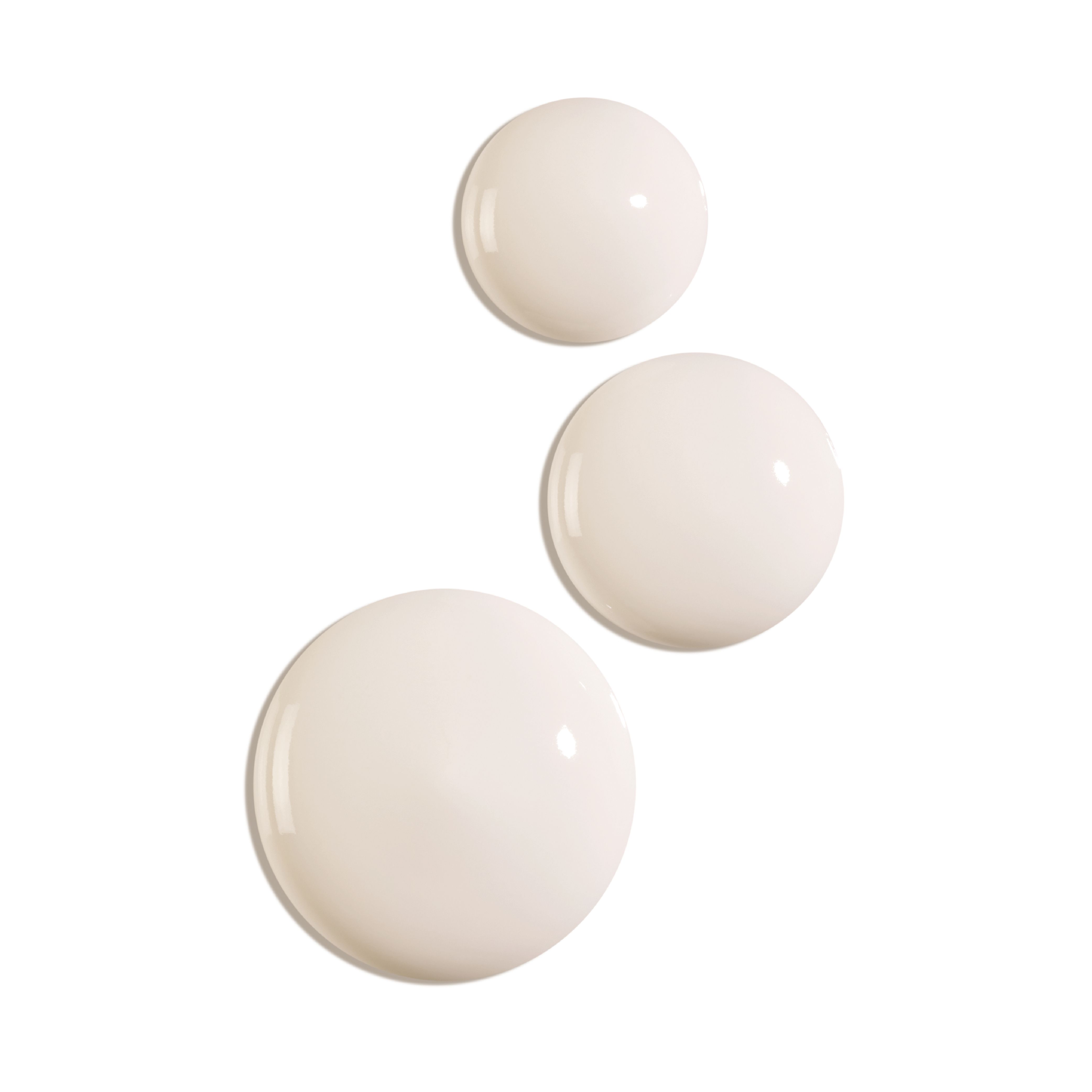 Drei Tropfen einer weißen Flüssigkeit. Runde Form, glatte Oberfläche. Auf weißem Hintergrund.