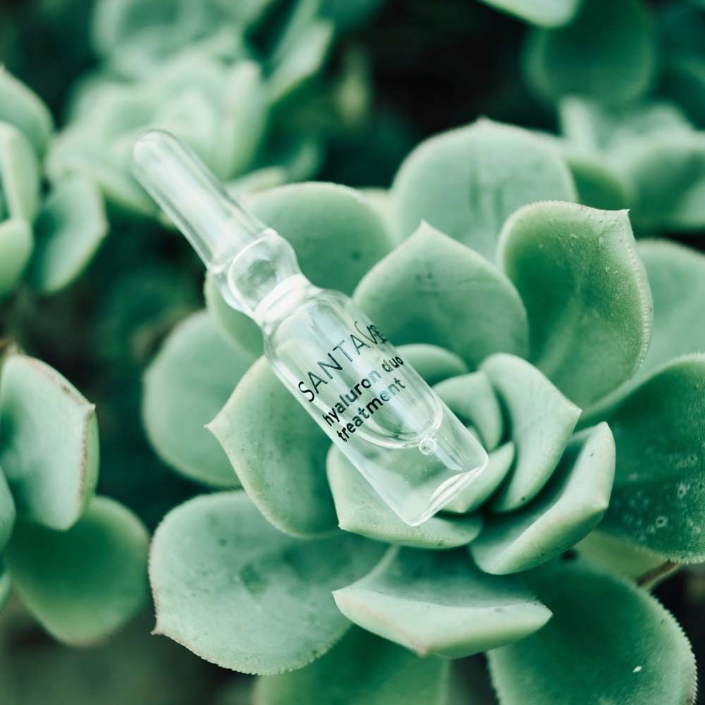 Ampulle mit SANTAVERDE-Aufdruck, auf grünen Blättern. Klare Flüssigkeit.