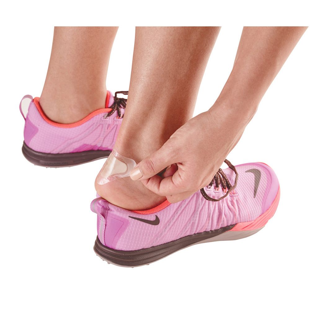 Person bringt Blasenpflaster an der Ferse an. Pinke Sportschuhe.