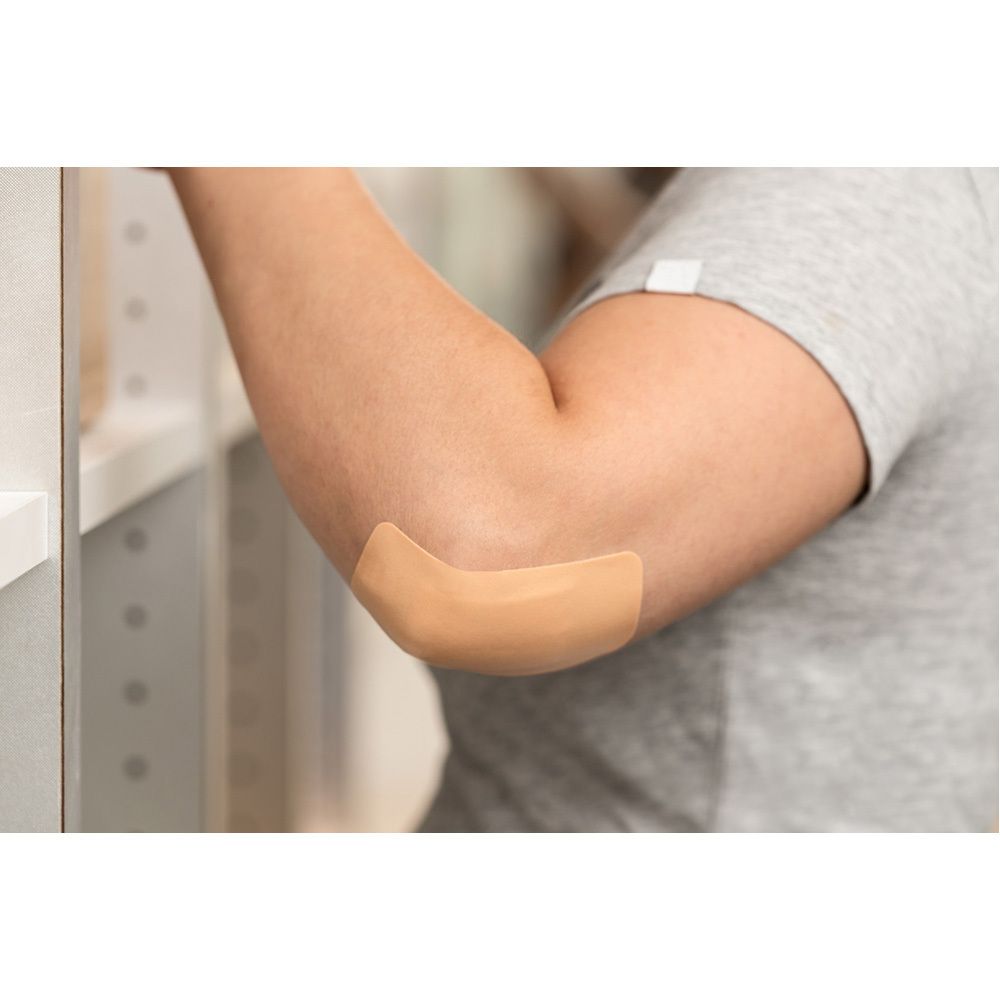 Ein beige Pflaster auf einem Ellbogen. Die Haut ist sichtbar.