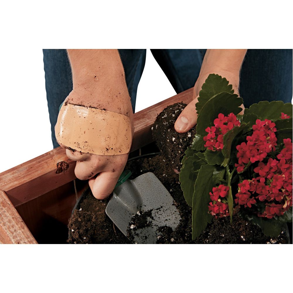 Ein beige Pflaster auf einer Hand, die in Erde arbeitet.