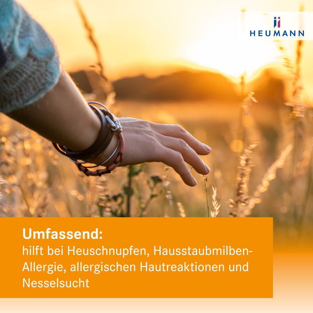 Hand berührt Grashalme. Text: Hilft bei Heuschnupfen, Hausstaubmilbenallergie, allergischen Hautreaktionen und Nesselsucht. Marke: Heumann.