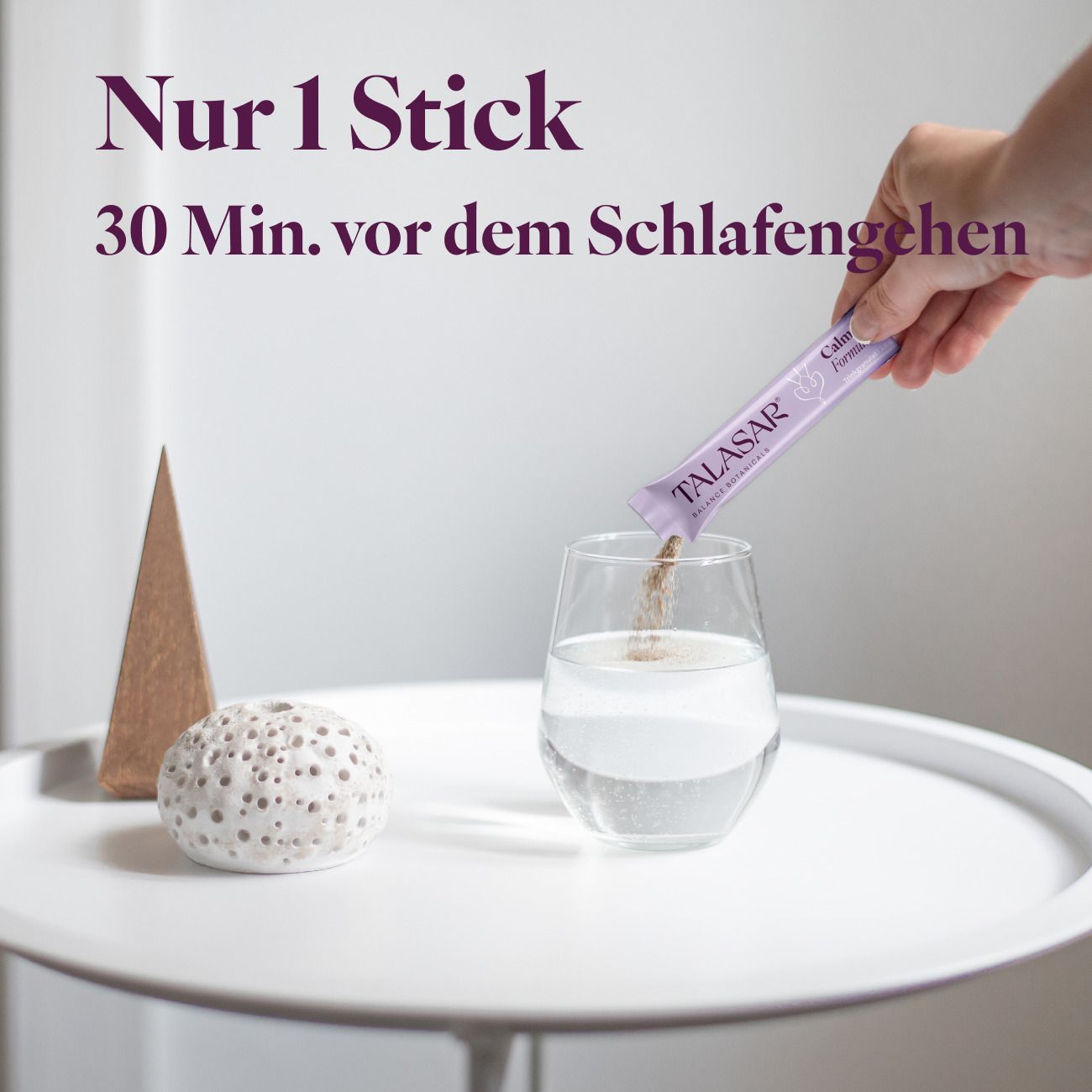 Person gießt Granulat aus einem Stick "TALASAR Calm Night Formula" in ein Glas Wasser.