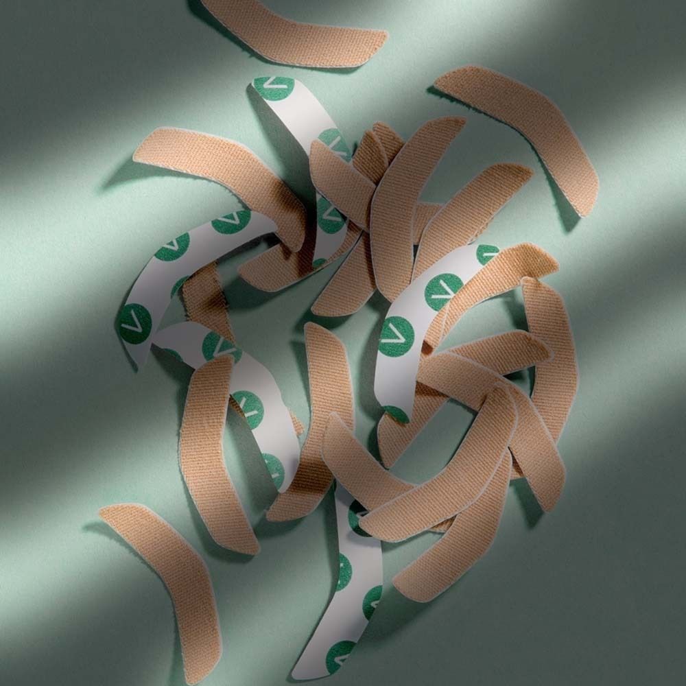 Mehrere Mund-Patches auf grünem Untergrund. Beige Patches mit grünem Aufdruck.