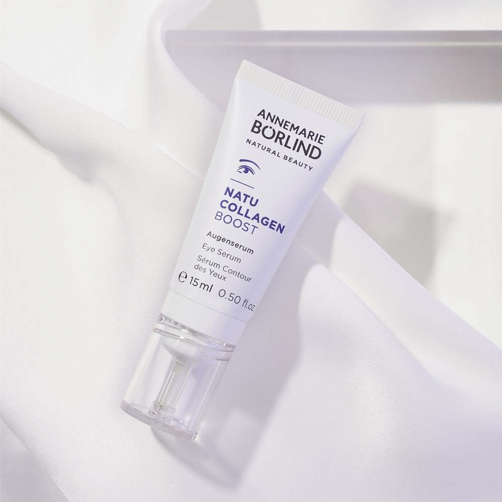 Weiße Tube mit lila Schrift. Enthält Augenserum. Marke: ANNEMARIE BÖRLIND. Auf weißem Stoff.