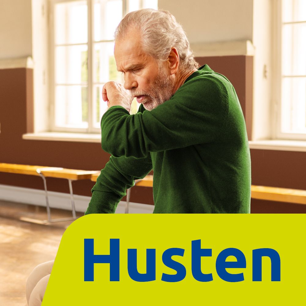 Älterer Mann hustet. Gelber Hintergrund mit Schriftzug Husten. Innenraum mit Fenstern und Bänken.