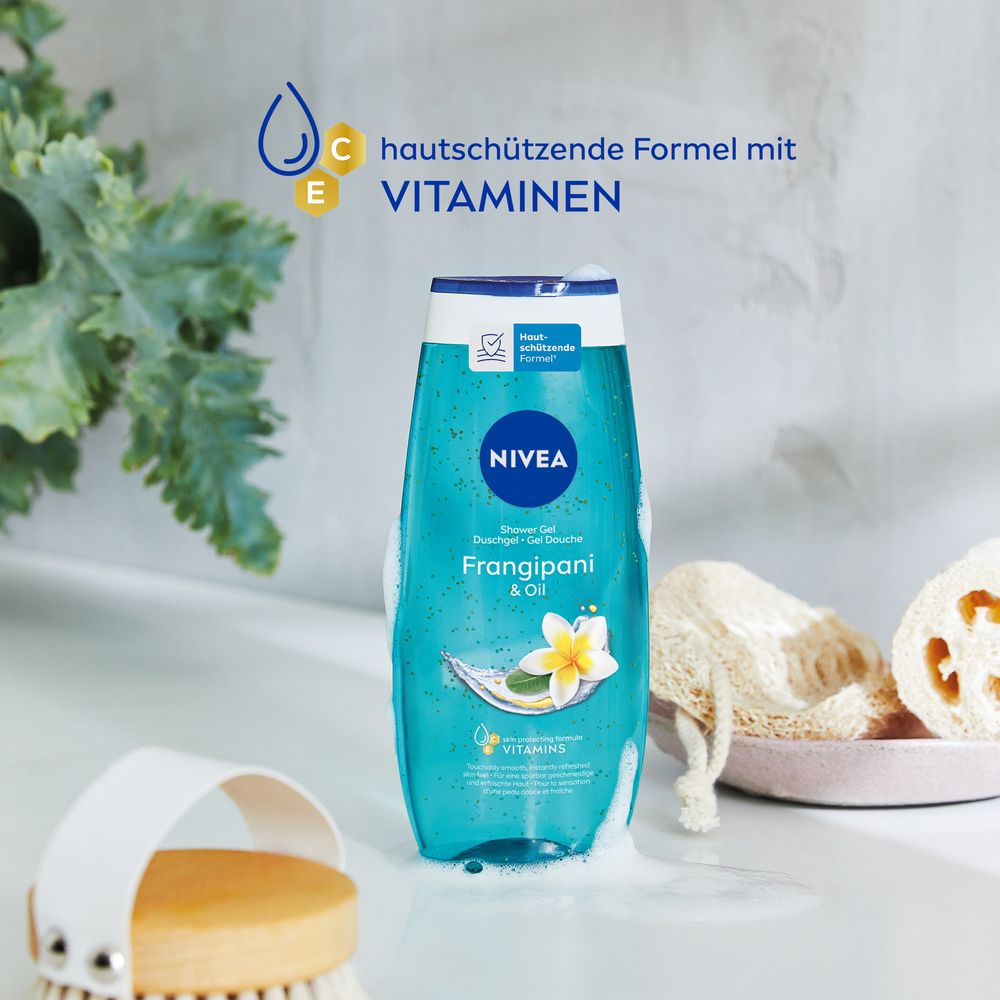 NIVEA Frangipani & Oil Pflegedusche in einer natürlichen Umgebung mit Pflanzen und Badeaccessoires. Formel mit Vitaminen hervorgehoben.