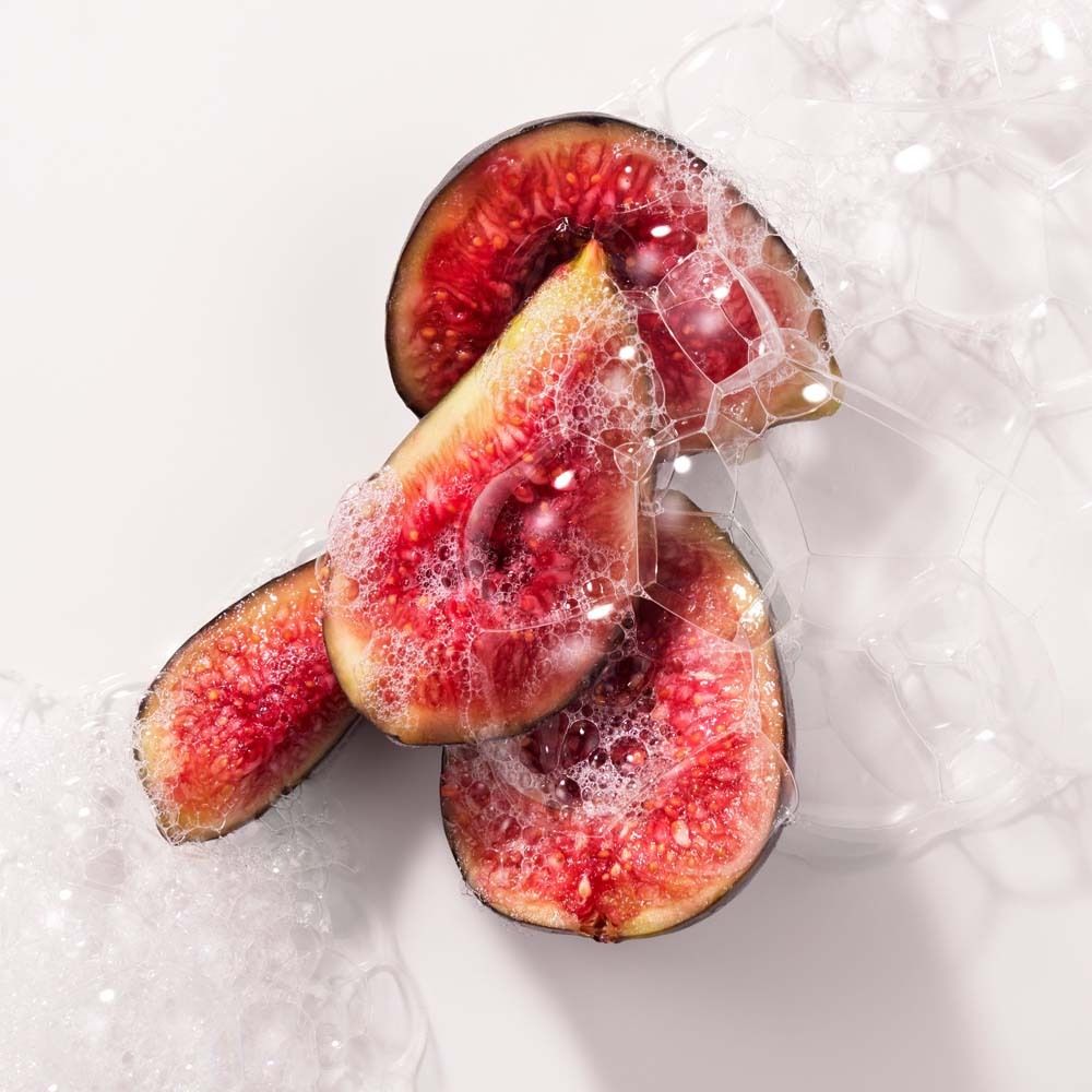 Aufgeschnittene Feigen in Seifenblasen. Rote Fruchtfleisch, dunkle Schale. Weißer Hintergrund. Nahaufnahme.
