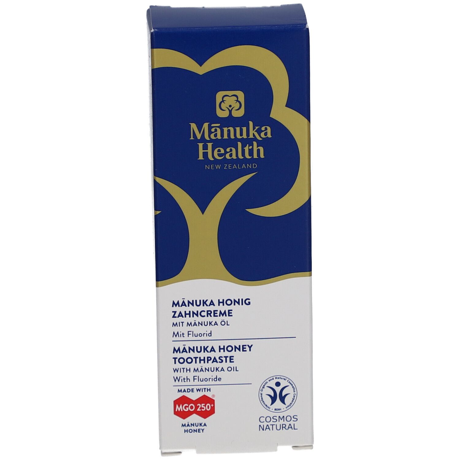 Zahncreme-Schachtel. Blau-weißes Design mit Logo und Schriftzug. Enthält Manuka-Honig und Fluorid. COSMOS NATURAL-Zertifizierung.