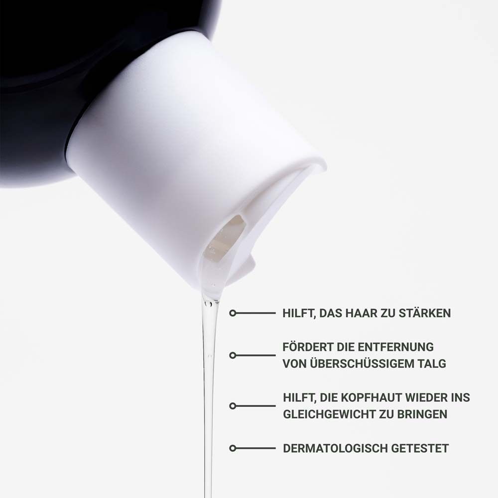 Nahaufnahme einer Shampoo-Flasche. Text: Hilft, das Haar zu stärken, die Kopfhaut ins Gleichgewicht zu bringen.