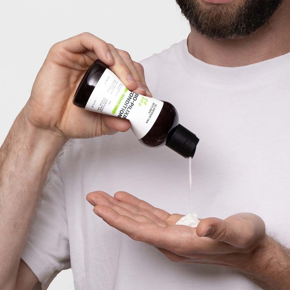 Mann gießt Conditioner in die Handfläche. Braune Flasche mit schwarzem Deckel. Produkt: BIO-PILIXIN Conditioner.