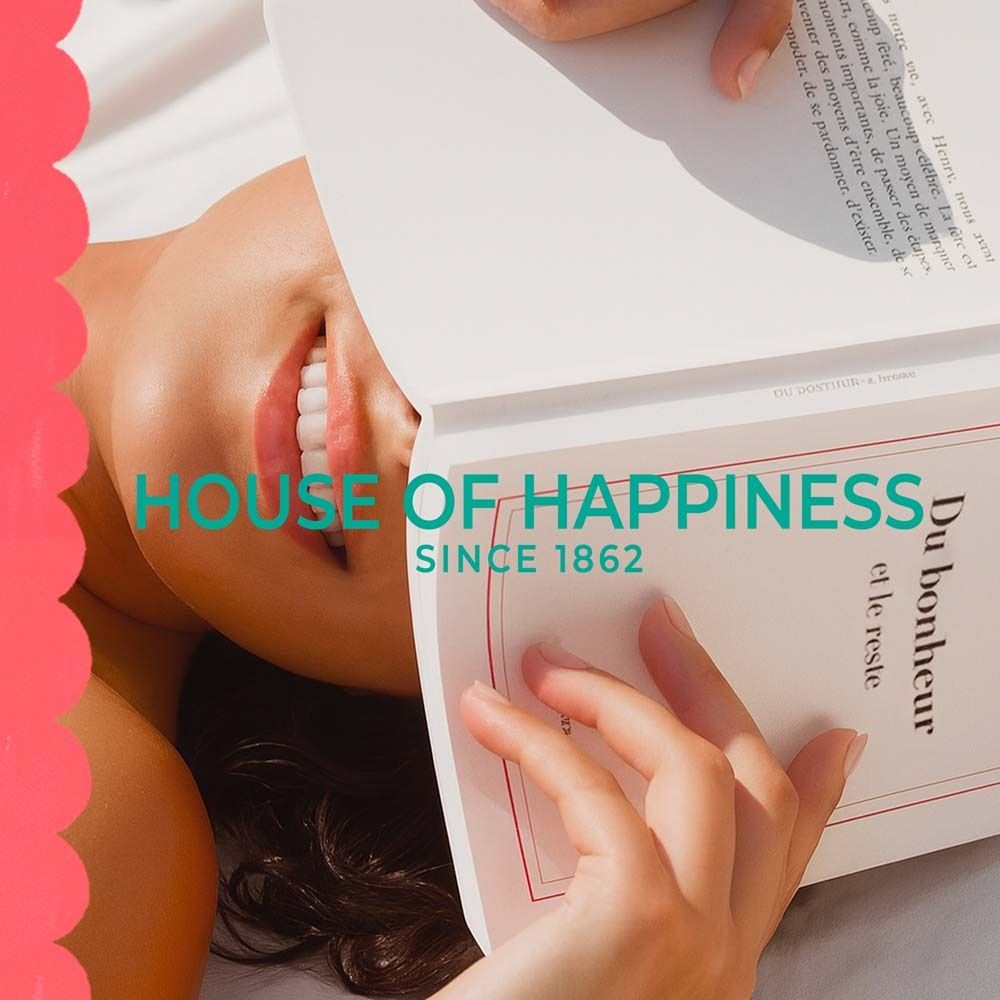 Frau liest Buch. Text: House of Happiness, Since 1862. Buch mit französischem Text.