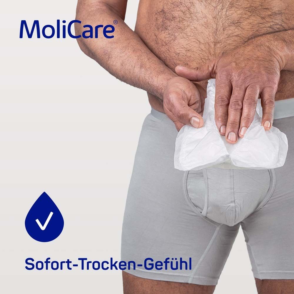 Mann hält MoliCare MEN Pad. Sofort-Trocken-Gefühl. Anatomische Form.