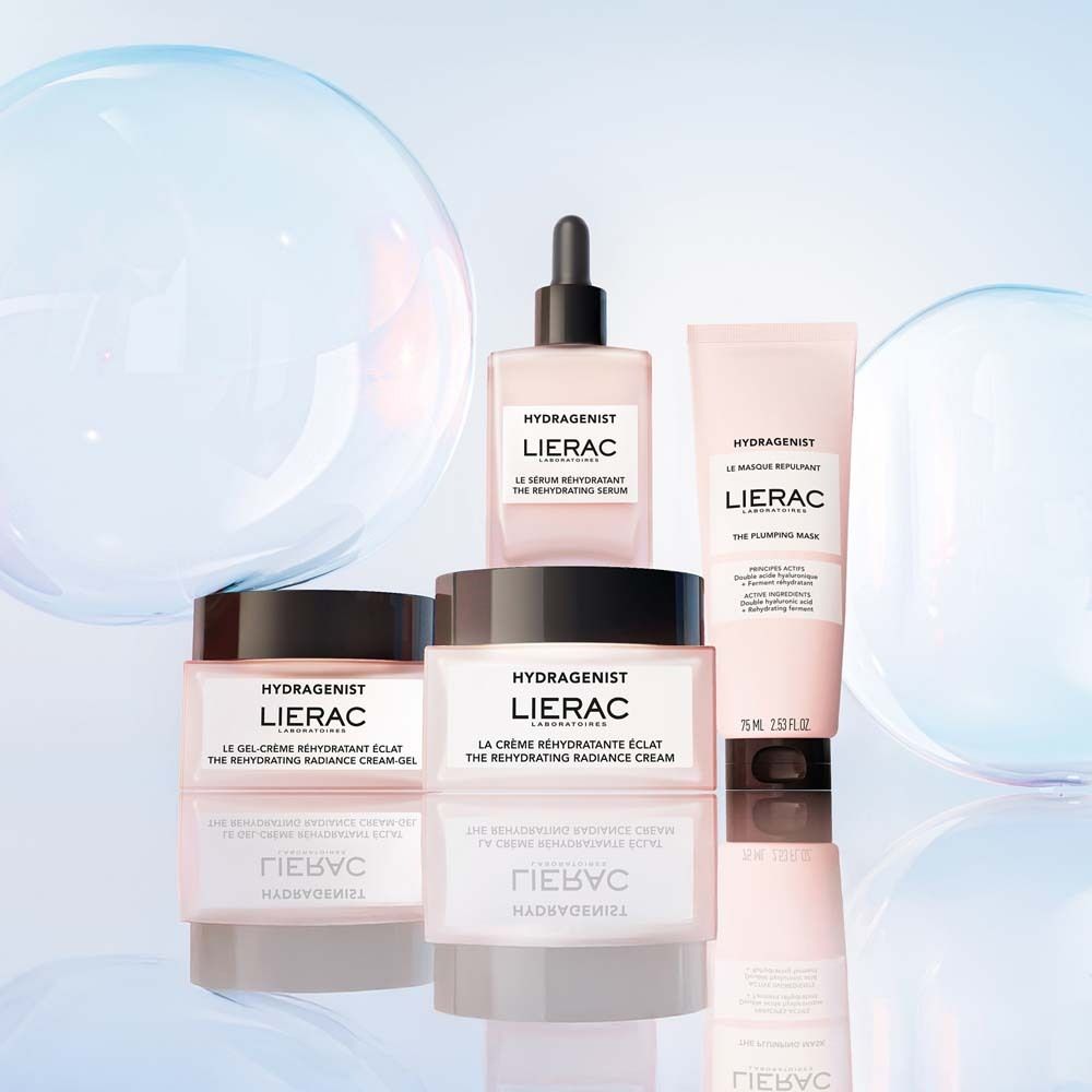Verschiedene LIERAC Produkte: Creme, Serum, Maske. Rosa Verpackung. Auf blauem Hintergrund mit Blasen.