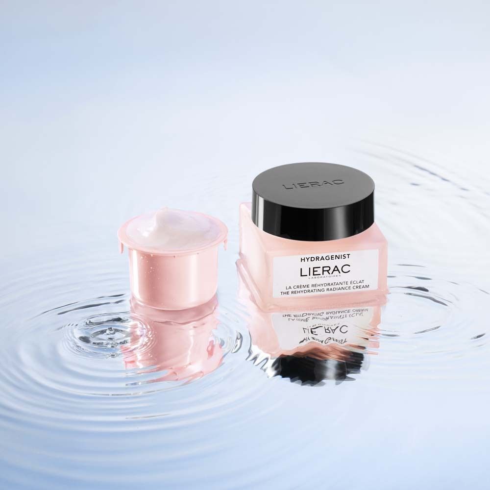 Rosa Creme-Tiegel und Nachfüllpackung im Wasser. Schwarzer Deckel mit LIERAC-Logo.