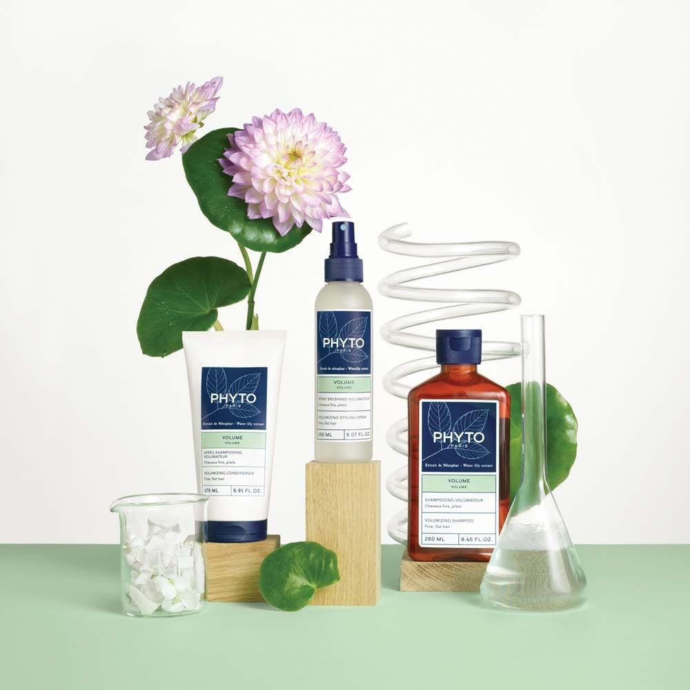 PHYTO PARIS Produkte: Föhnspray, Shampoo, Creme. Auf Holzblöcken, mit Blumen und Laborutensilien. Text: Volume, Creme, Shampoo.