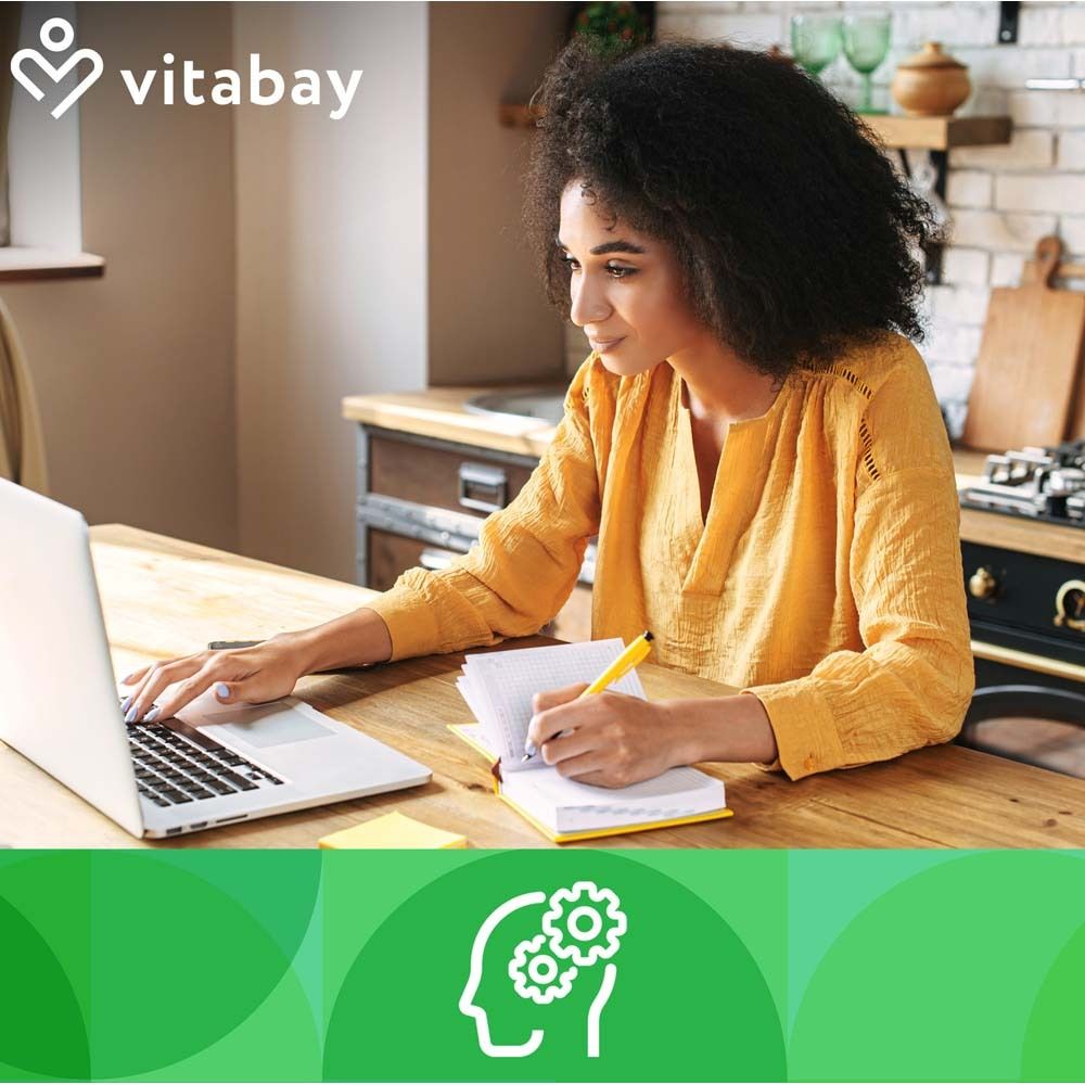 Frau arbeitet am Laptop. Grünlippmuschel-Symbol. Vitabay-Logo. Hintergrund: Küche, Notizbuch, Stift.