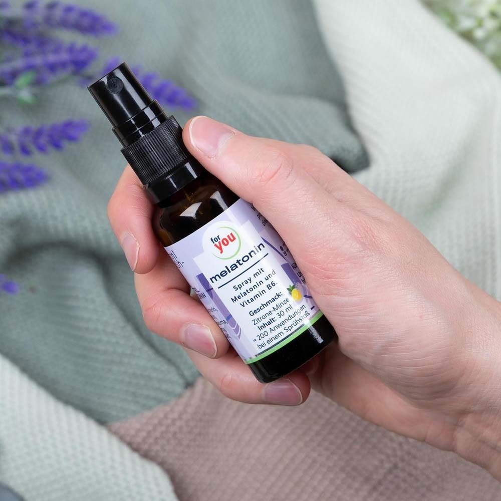 Hand hält eine braune Sprühflasche. Aufschrift: for you melatonin. Enthält Melatonin und Vitamin B6. Geschmack: Zitrone-Minze.