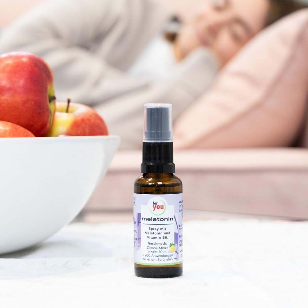 Braune Sprühflasche neben einer Schüssel mit Äpfeln. Aufschrift: for you melatonin. Enthält Melatonin und Vitamin B6. Geschmack: Zitrone-Minze.