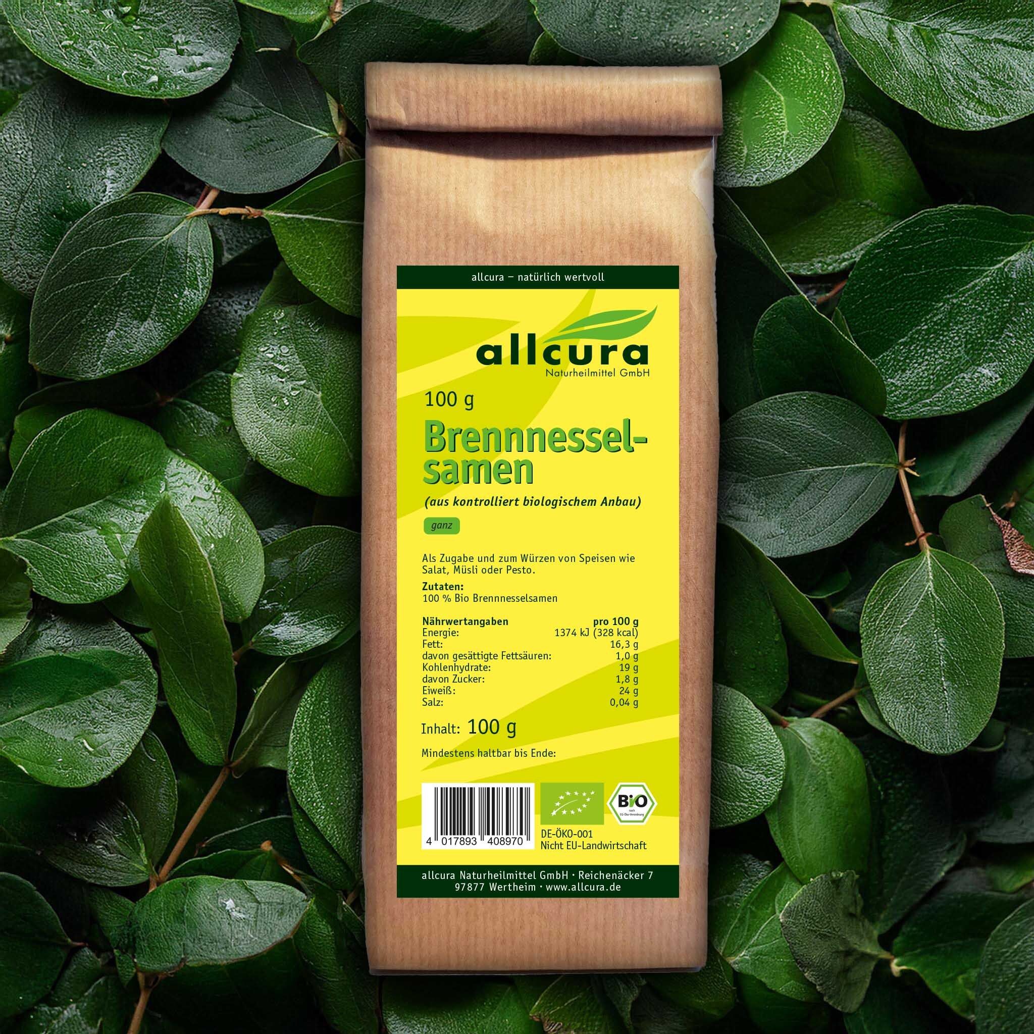 Braune Papiertüte mit grünem Etikett, umgeben von grünen Blättern. Aufschrift: allcura Brennnesselsamen Bio. Bio-Siegel. Nährwertangaben.