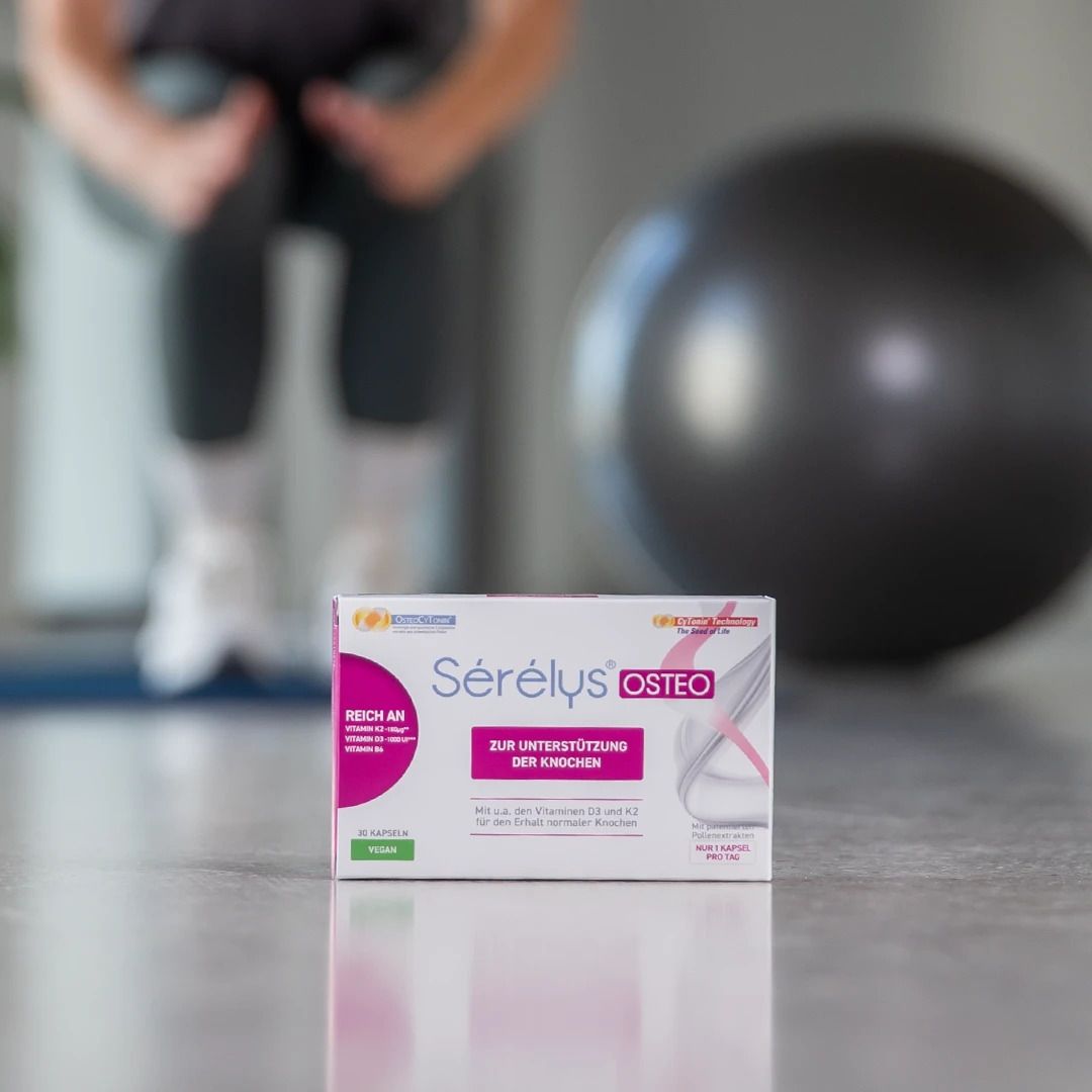 Sérélys OSTEO-Verpackung auf dem Boden. Im Hintergrund eine Person und ein Gymnastikball.