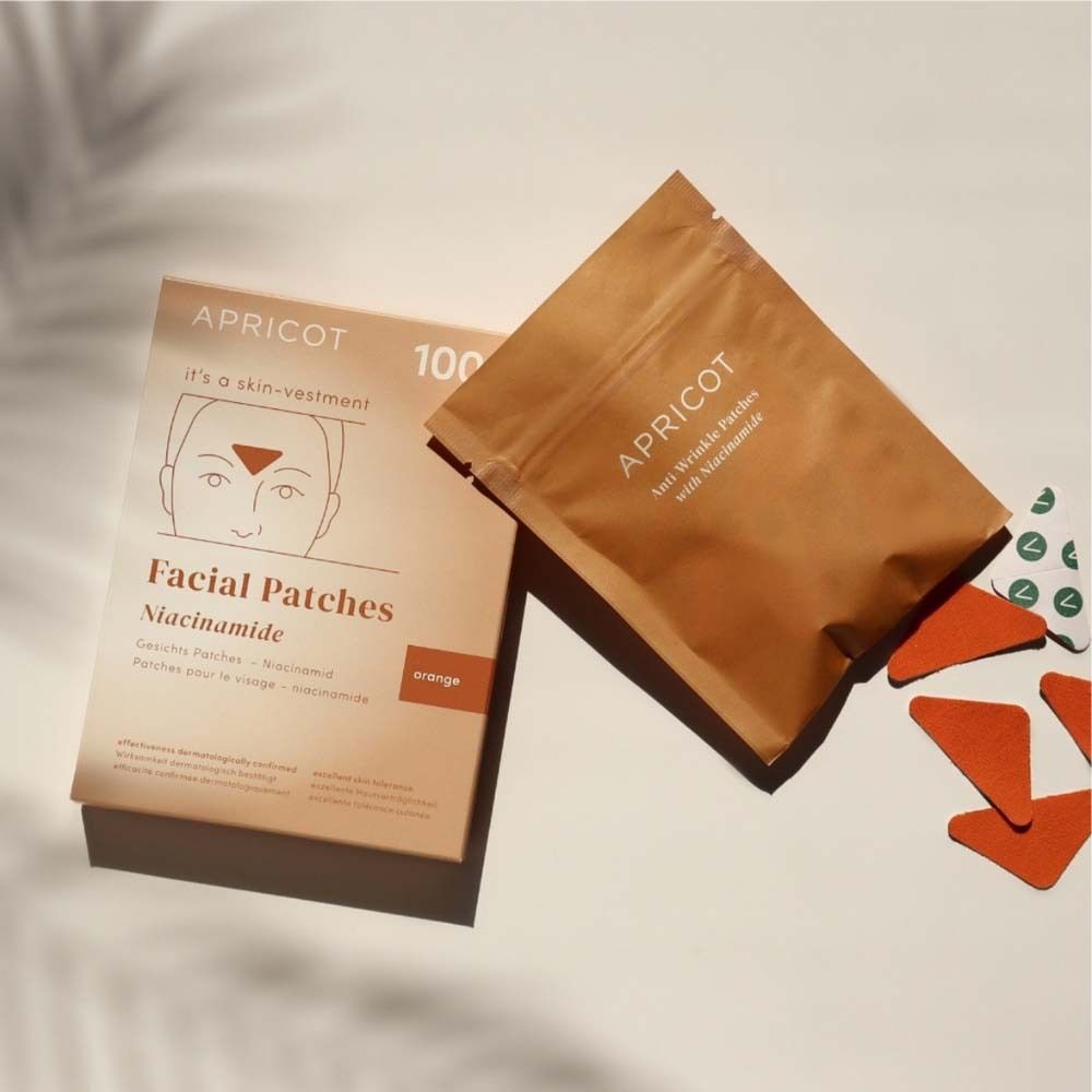 Verpackung und Beutel mit Gesichtspatches. Marke APRICOT. Orangefarbene Patches. Auf hellem Untergrund.